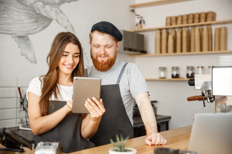 smiling baristas using a tablet in coffee shop